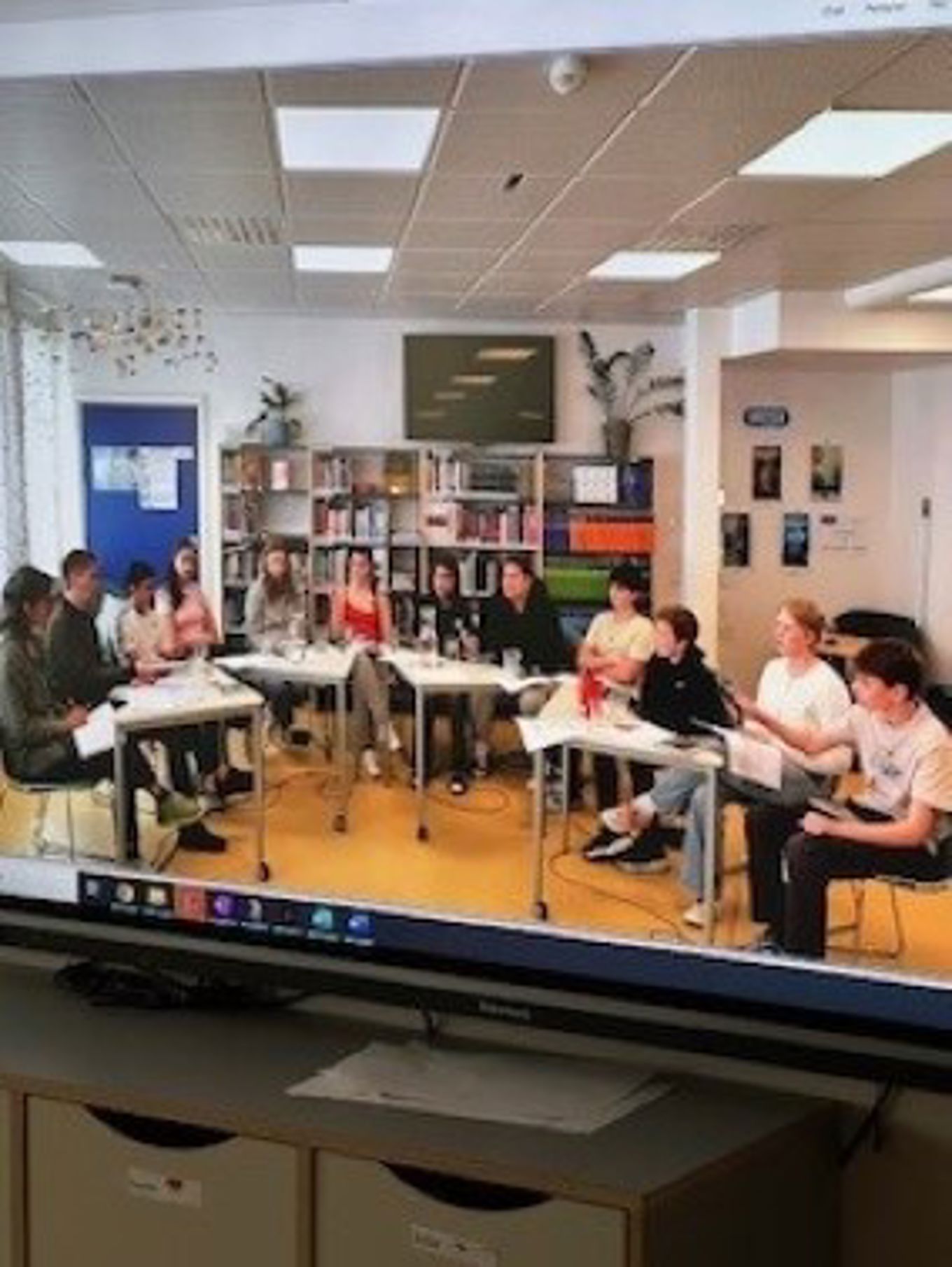 En gruppe mennesker som sitter ved pultene i et bibliotek